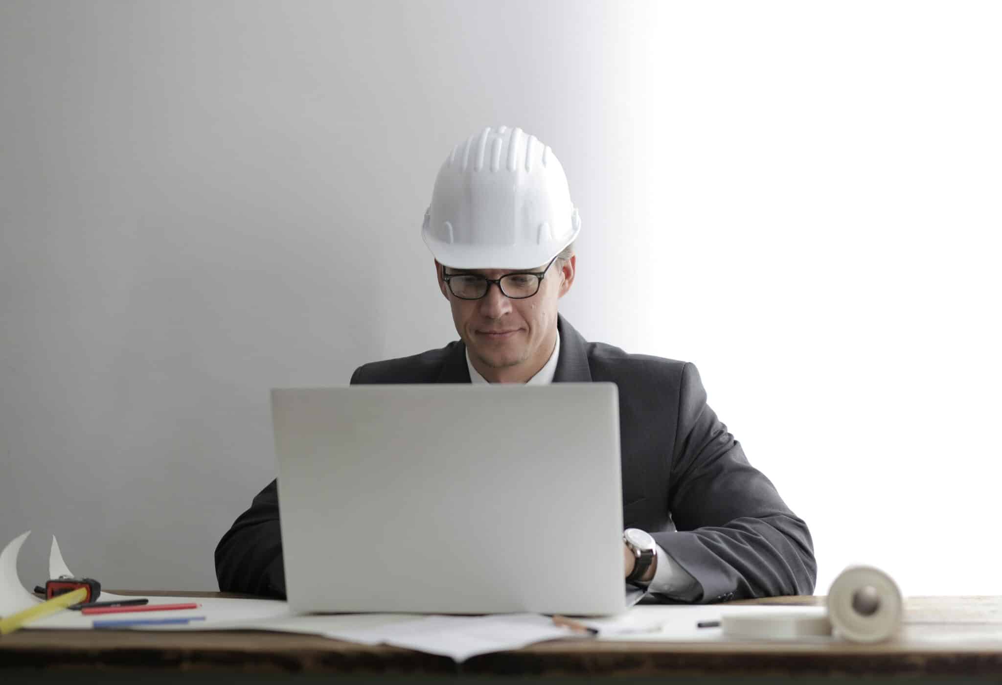 Construction Manager with Site Hard Hat Working on a Laptop